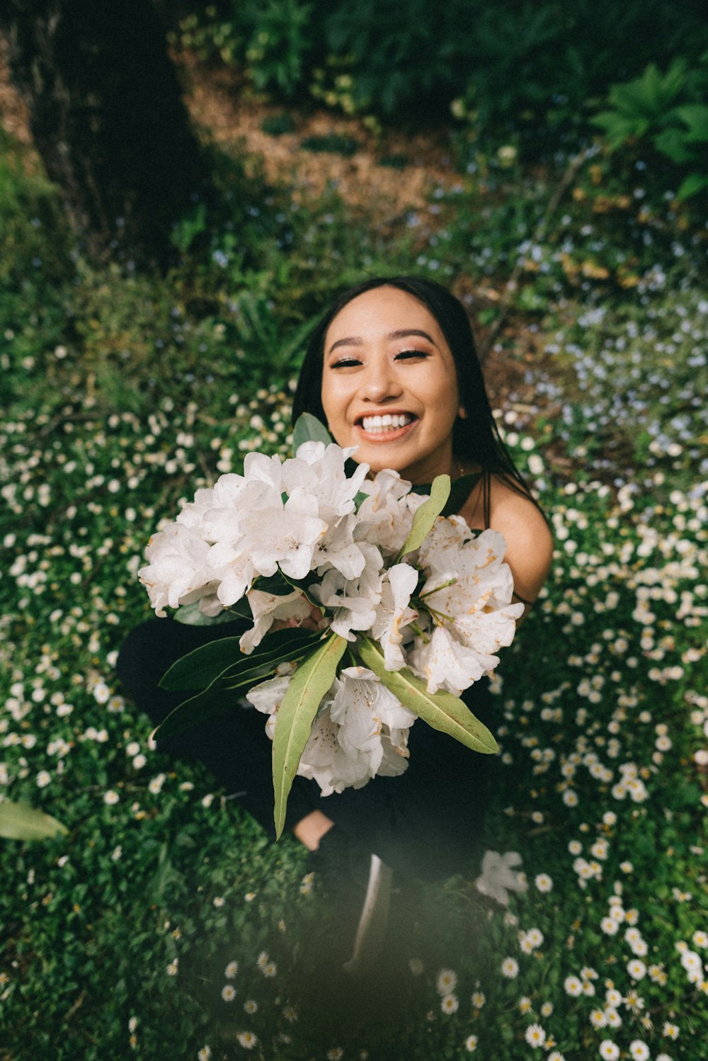 smiling woman holding a white petaled flowers