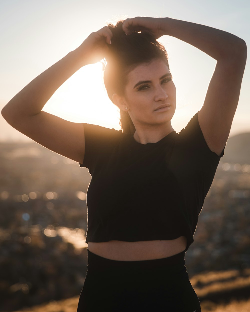 woman with hands over her head in black crop top