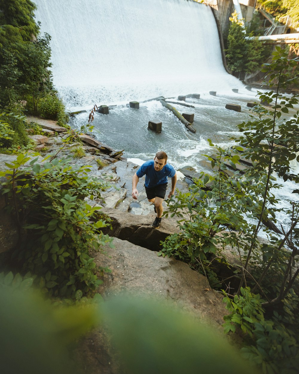 man climbing on cliff beside river