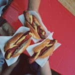 three persons holding hotdog buns