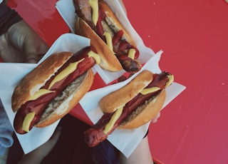 three persons holding hotdog buns