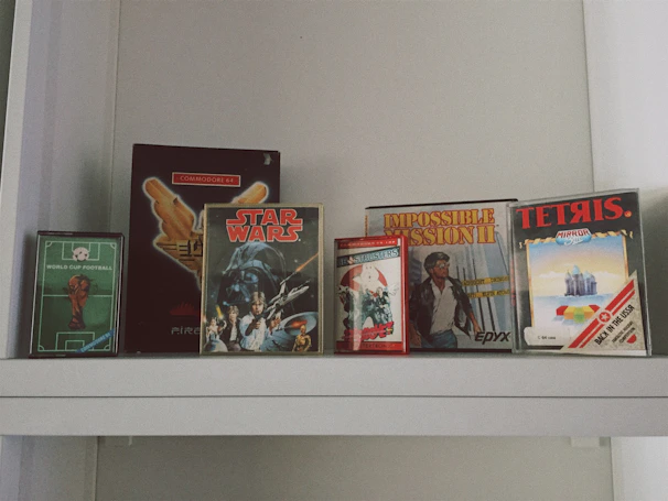A vibrant collection of vintage video game cartridges and retro consoles arranged on a wooden shelf.