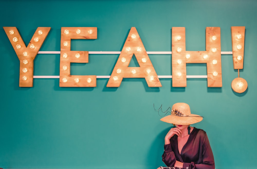 woman wearing brown hat near the yeah signage photography