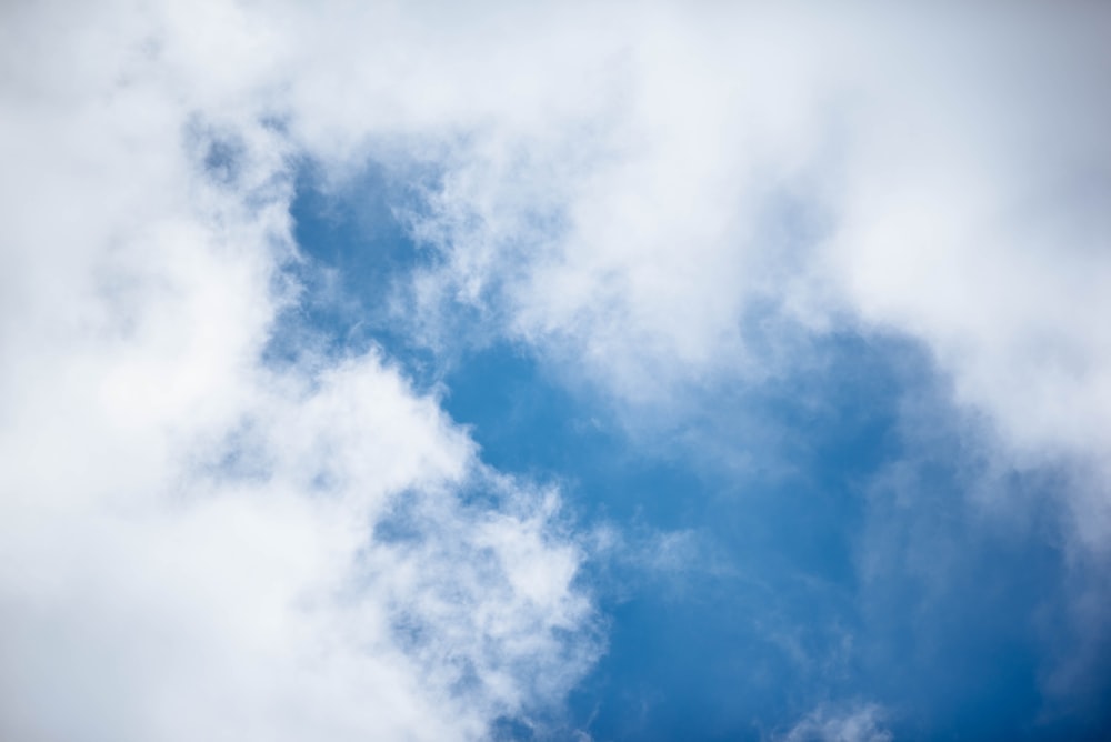 a plane flying through a cloudy blue sky