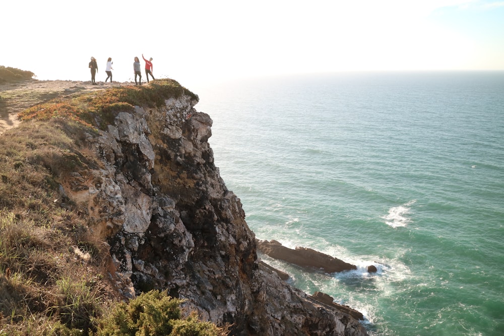four persons standing on the cliff