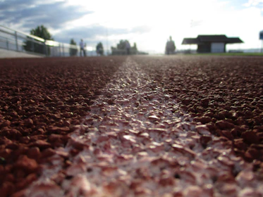 Close-up of a trainer adjusting a runner’s form on a bright, lively track.