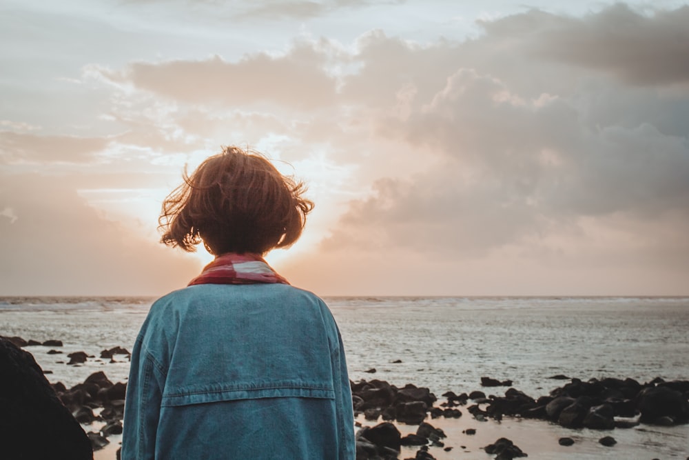 woman wearing denim jacket and facing at the seashore