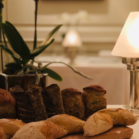 A rustic wooden table adorned with an assortment of breads, highlighted by soft natural light.