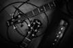 Two guitar headstocks are entangled with cables on a wooden surface. The guitar brands are prominently displayed, with tuning pegs and strings visible. The setup suggests a focus on instruments and possibly musical performance.