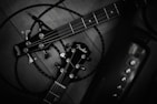 Two guitar headstocks are entangled with cables on a wooden surface. The guitar brands are prominently displayed, with tuning pegs and strings visible. The setup suggests a focus on instruments and possibly musical performance.