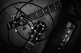 Two guitar headstocks are entangled with cables on a wooden surface. The guitar brands are prominently displayed, with tuning pegs and strings visible. The setup suggests a focus on instruments and possibly musical performance.
