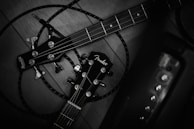 Two guitar headstocks are entangled with cables on a wooden surface. The guitar brands are prominently displayed, with tuning pegs and strings visible. The setup suggests a focus on instruments and possibly musical performance.