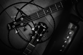 Two guitar headstocks are entangled with cables on a wooden surface. The guitar brands are prominently displayed, with tuning pegs and strings visible. The setup suggests a focus on instruments and possibly musical performance.