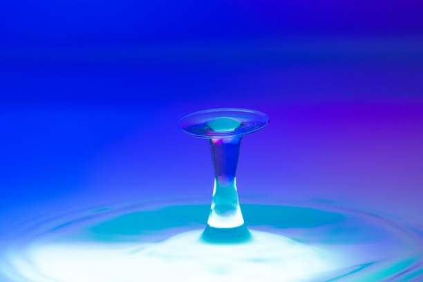 A sleek water droplet with glowing aqua blue waves flowing around it.
