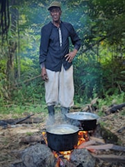 A person purifying water by a campfire with wild edible plants nearby