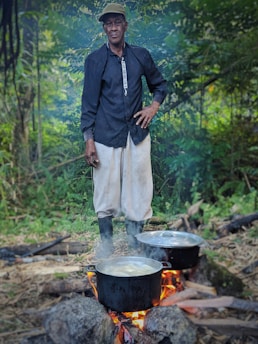 A person purifying water by a campfire with wild edible plants nearby
