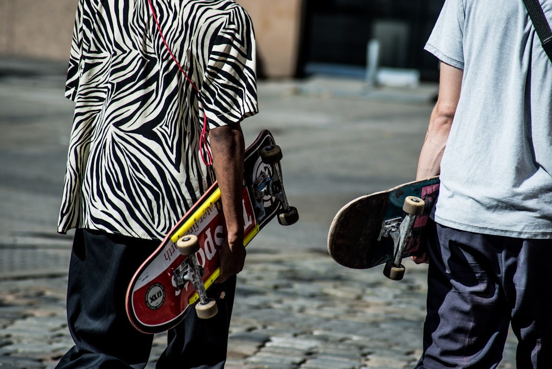 man holding skateboard while walking at street