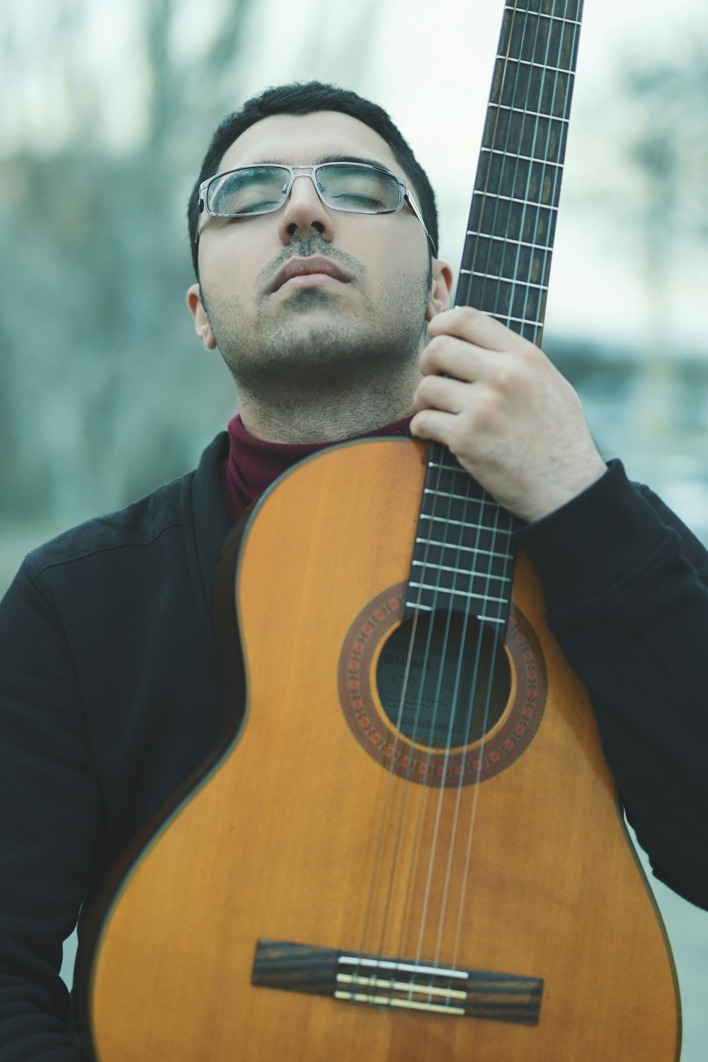 man holding brown acoustic guitar