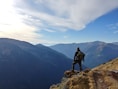 man on top of mountain under blue sky