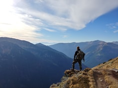 man on top of mountain under blue sky