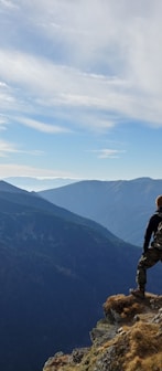 man on top of mountain under blue sky