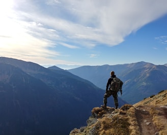 man on top of mountain under blue sky