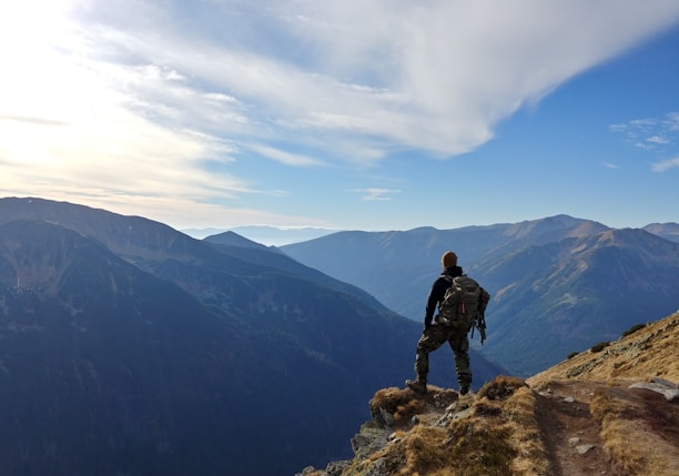 man on top of mountain under blue sky