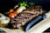 Close-up of a gourmet grilled steak served on a rustic wooden board.