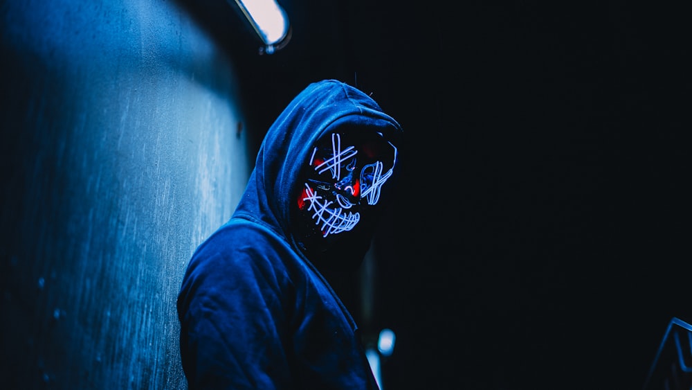 man wearing mask leaning on wall