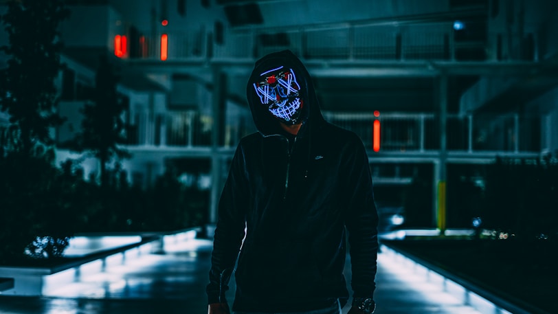 standing man in black jacket with mask