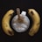 A creamy beverage topped with a banana slice and a straw rests between two ripe bananas on a dark surface.