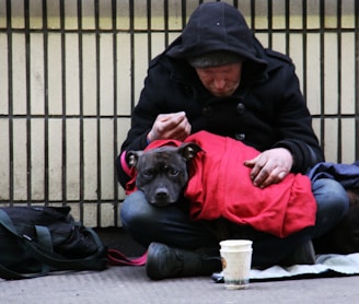 dog on top of person's lap while sitting on ground at daytime