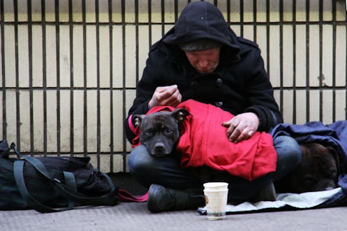 dog on top of person's lap while sitting on ground at daytime