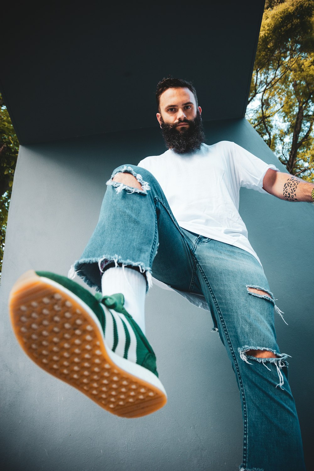 man standing near gray painted wall raising right leg at daytime