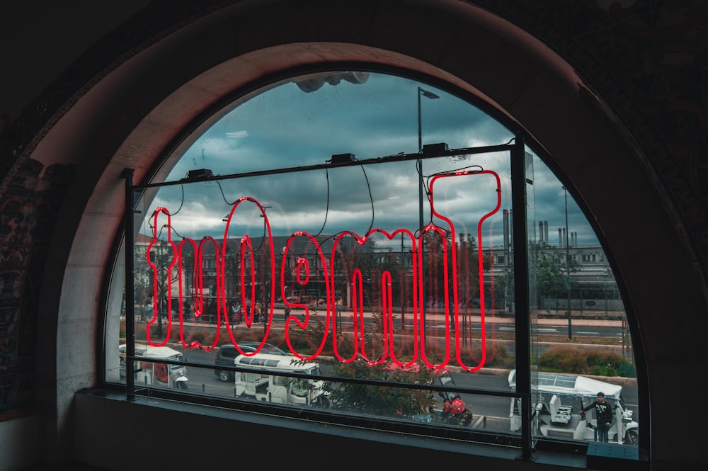 red neon signage placed on window panel