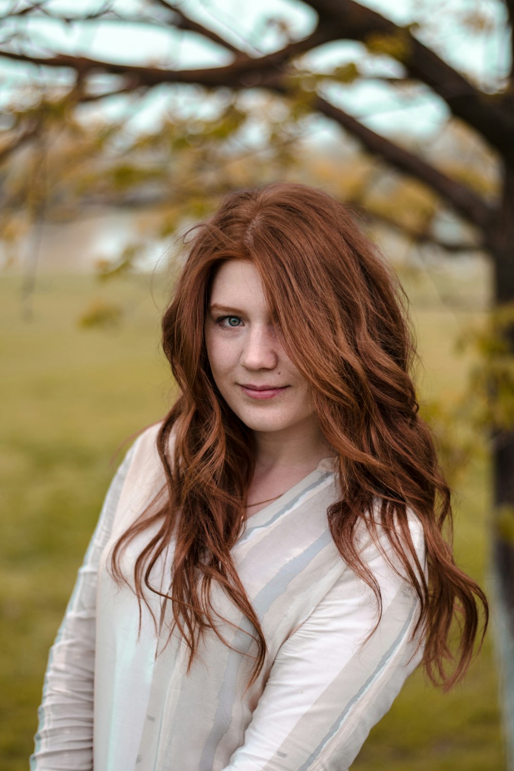 smiling woman in white and gray long-sleeved shirt