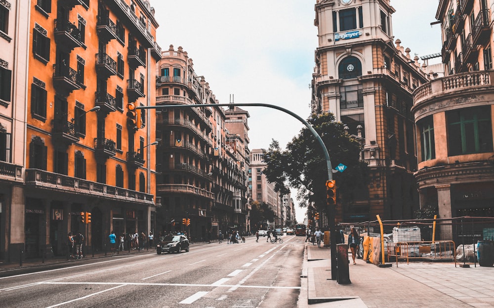 few cars on road and people walkingnear buildings