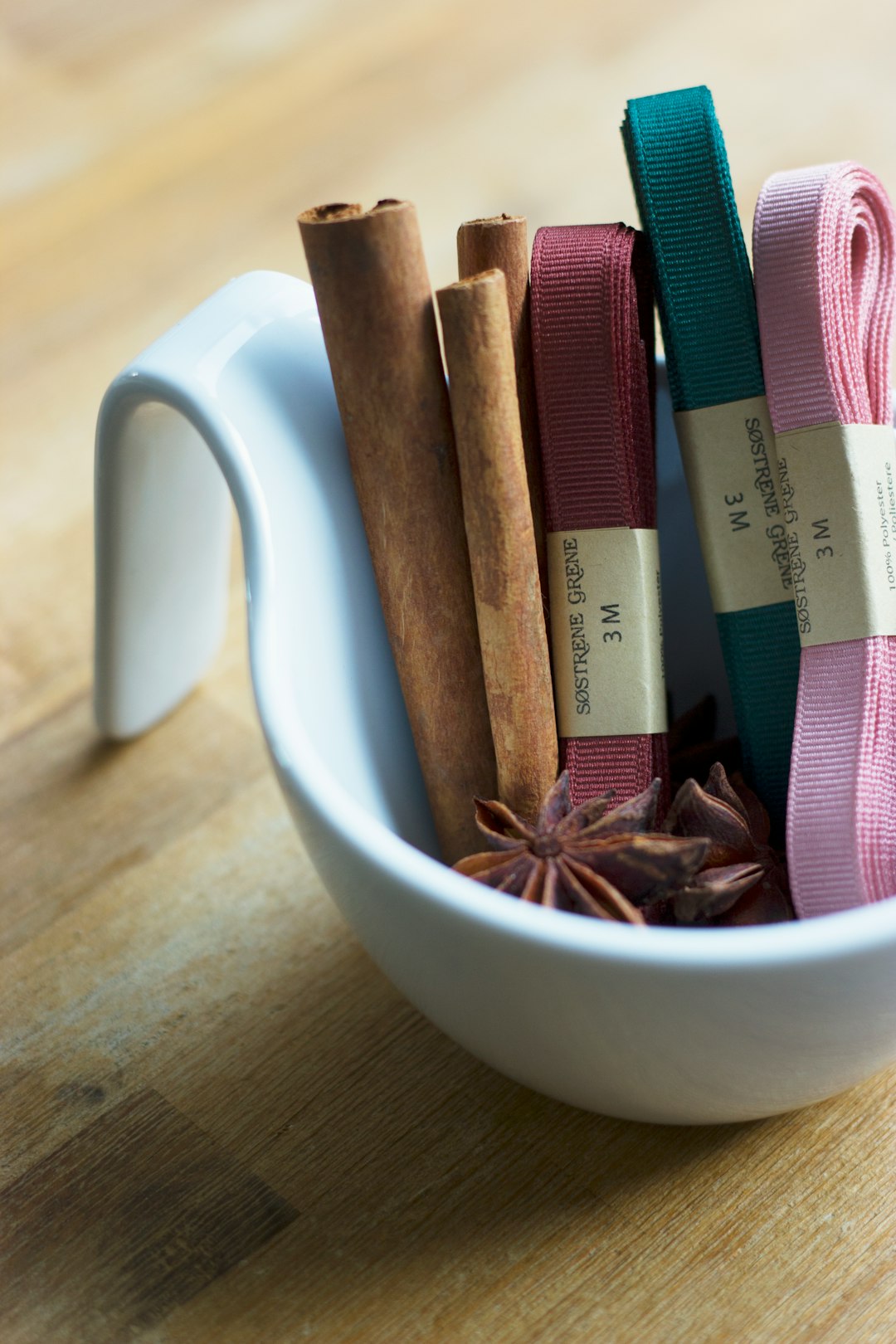 star anise, cinnamon roll, and several garters on round white ceramic bowl on top of brown surface