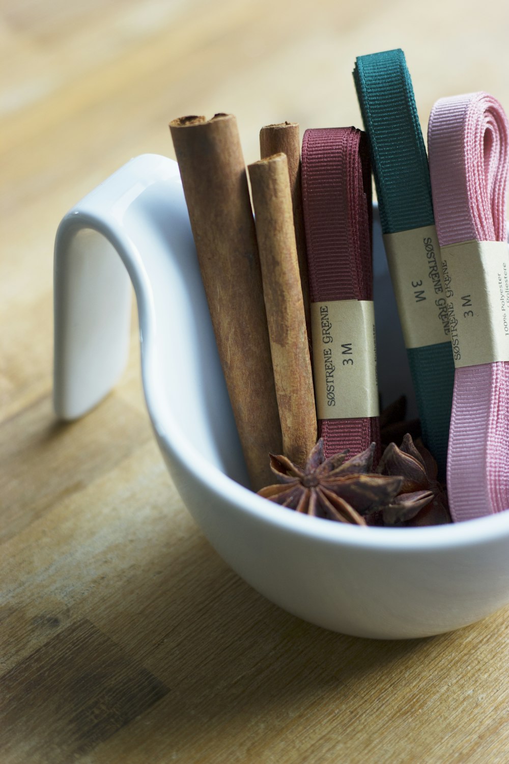 star anise, cinnamon roll, and several garters on round white ceramic bowl on top of brown surface