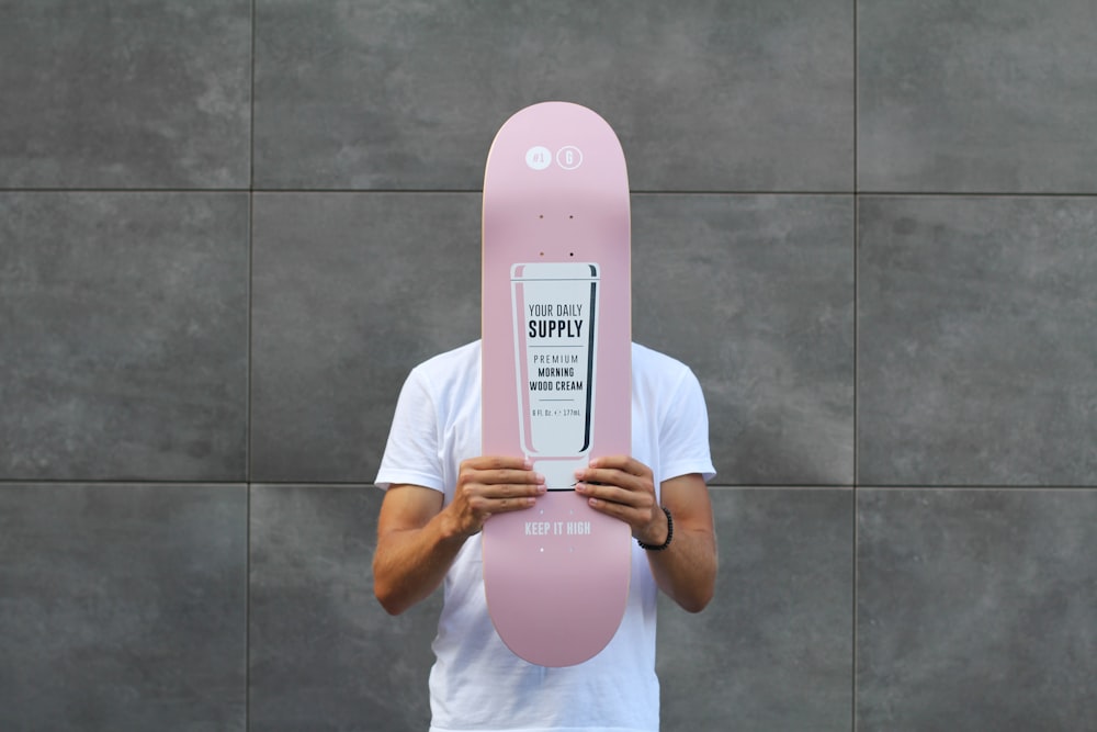 hombre sosteniendo una tabla rosa sobre su cara