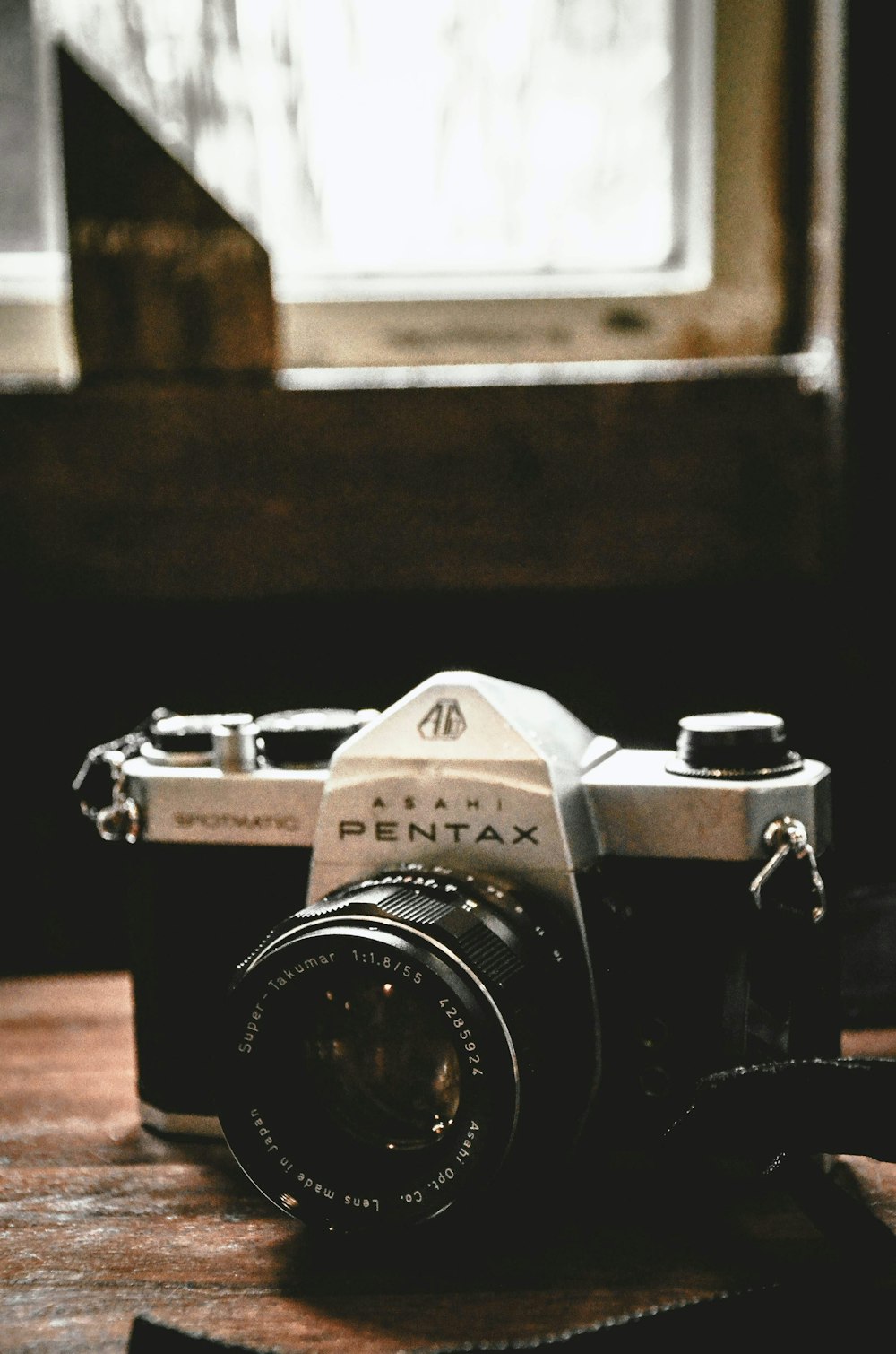 black and silver Pentax camera on table