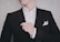 Close-up of a man confidently adjusting his jacket sleeve in a bright, minimalist room.