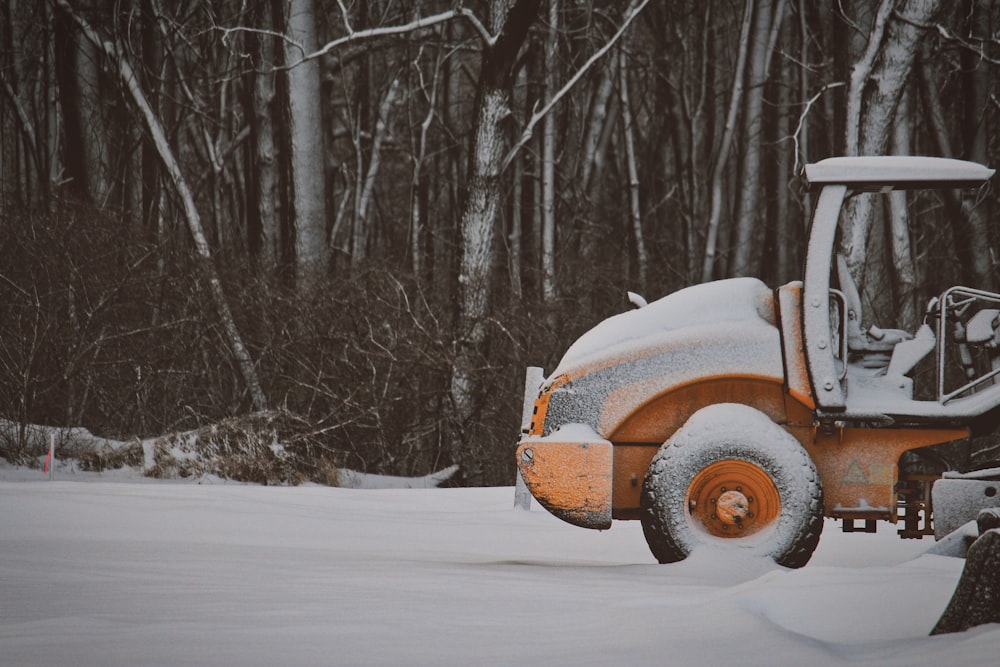 yellow truck covered with snow near trees