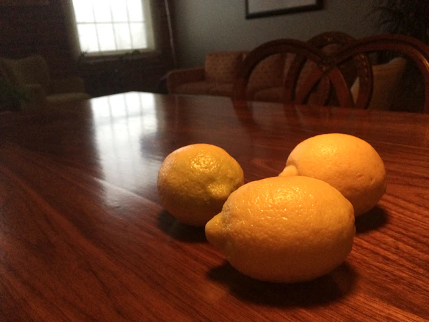A bright, fresh lemon resting on a rustic wooden table with sunlight streaming in.