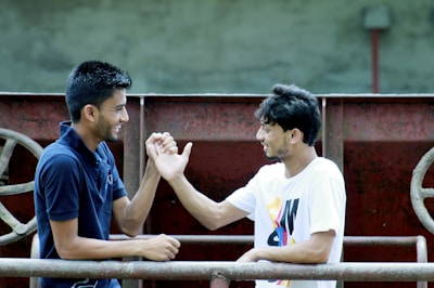 Two people exchanging scrap materials with a friendly handshake outdoors.