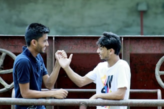 A friendly trainer and young athlete shaking hands outdoors on a sunny day.