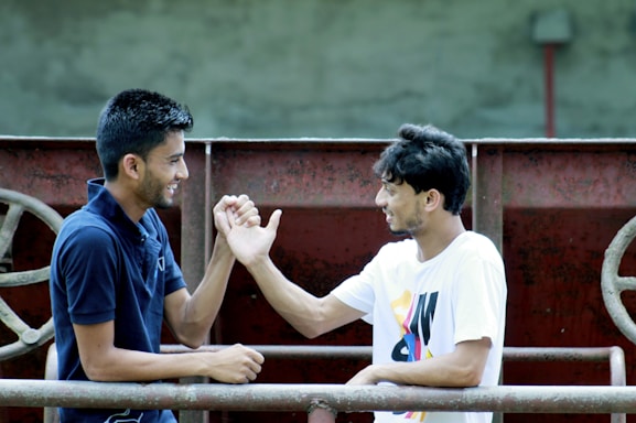 A friendly trainer and young athlete shaking hands outdoors on a sunny day.