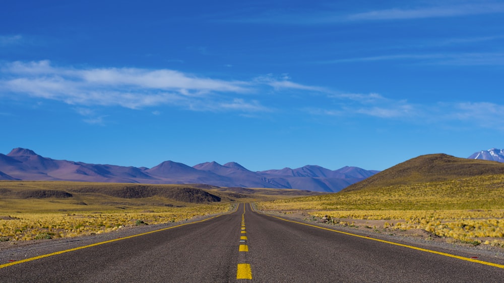 empty paved road near mountains during daytime