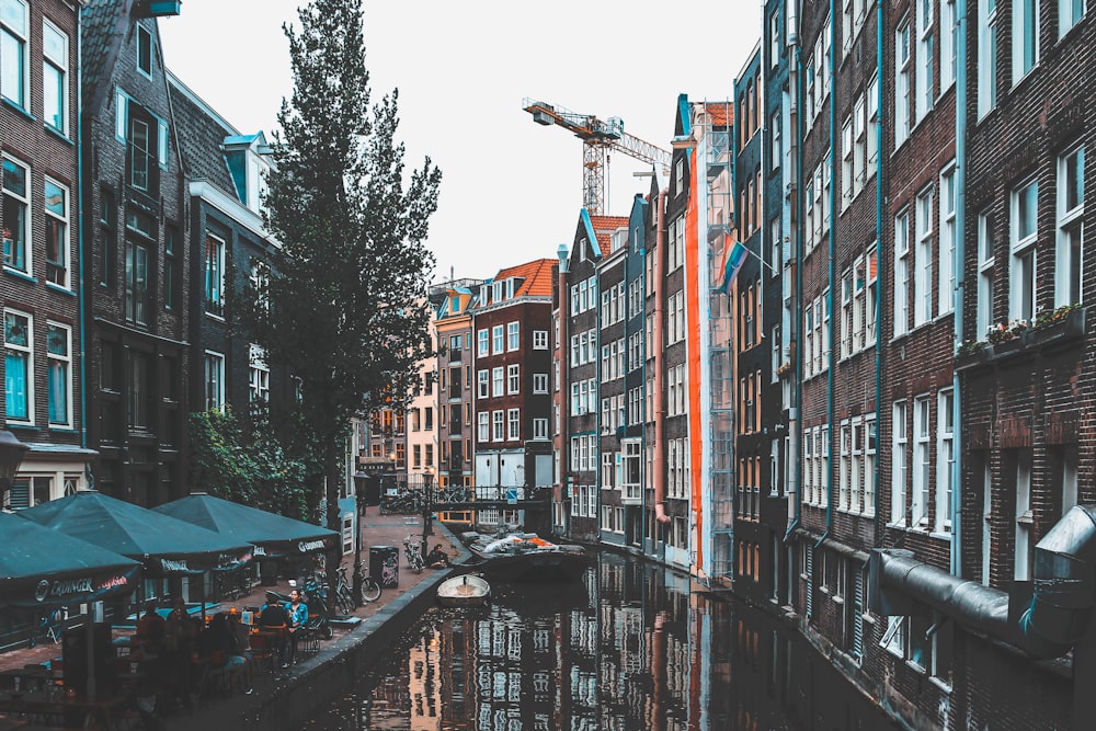 buildings beside canal and parasols during day