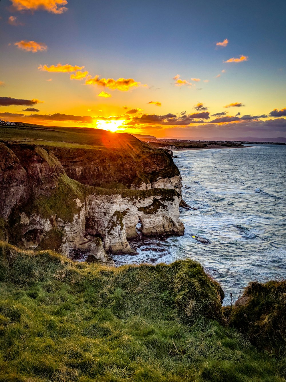 cliff beside body of water during sunset